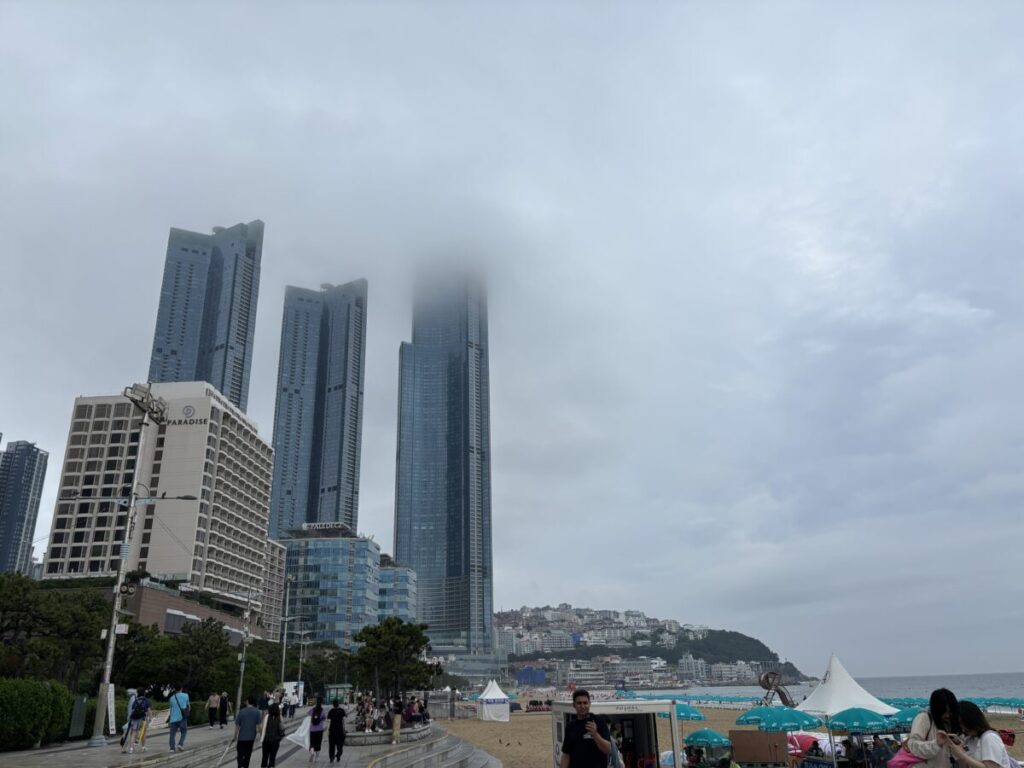 釜山ビーチの眺め。ビルのBUSAN X the SKYの上部が雲で隠れている。