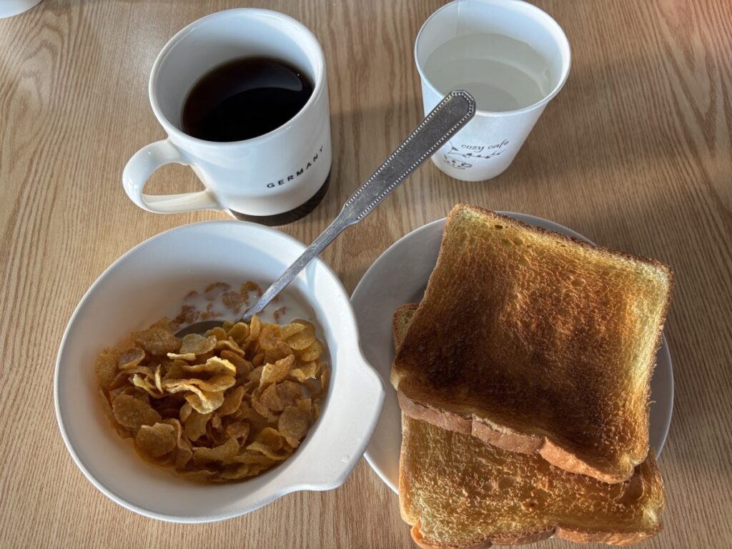 コーヒー、コーンフレーク、食パンを写した写真
